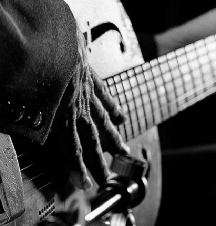 A black and white photo of a hand resting on a guitar