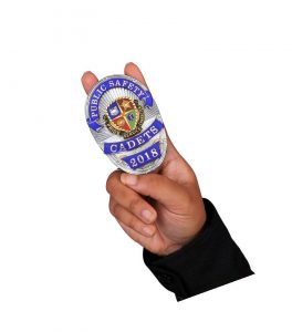Hand holding up Public Safety Cadets badge